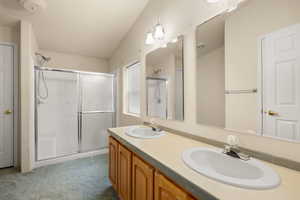Full bath featuring a shower stall and double vanity
