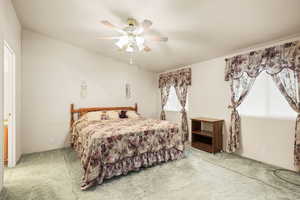 Carpeted bedroom with a ceiling fan