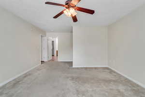 Carpeted spare room with baseboards and ceiling fan