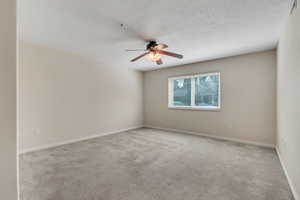 Empty room featuring carpet flooring and a ceiling fan