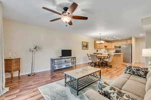 Living room with light wood finished floors, a ceiling fan, recessed lighting, and a chandelier