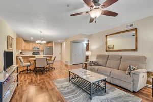 Living area featuring light wood-style flooring, a chandelier, and a ceiling fan