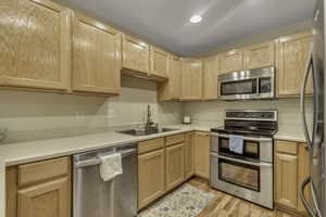 Kitchen featuring light brown cabinetry, appliances with stainless steel finishes, light countertops, light wood finished floors, and recessed lighting