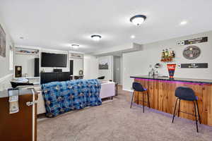 Living area with a textured ceiling, light colored carpet, and a wet bar