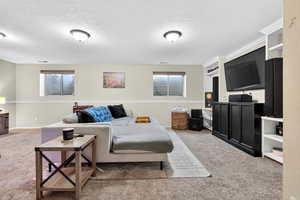 Carpeted living area with a textured ceiling and baseboards