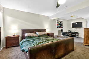 Bedroom featuring carpet, a ceiling fan, an office area, and a textured ceiling