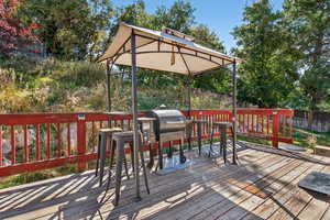 Wooden deck with a gazebo and area for grilling