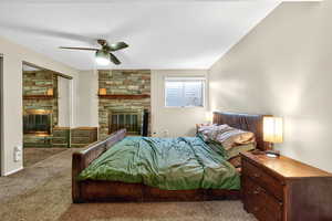 Carpeted bedroom with a fireplace, a ceiling fan, and a textured ceiling