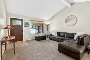 Living area featuring carpet, beam ceiling, and high vaulted ceiling