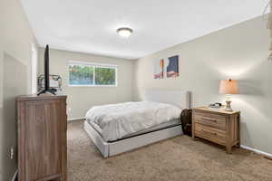 Carpeted bedroom with a textured ceiling and baseboards