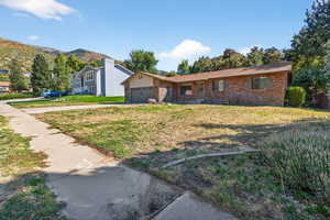 View of front of home with a front yard, brick siding, an attached garage, and a mountain view