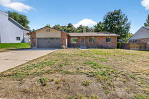 Ranch-style home with driveway, brick siding, and an attached garage
