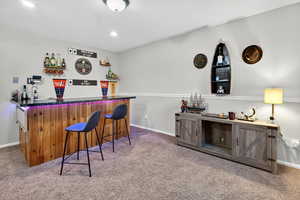 Indoor wet bar featuring dark countertops, carpet floors, a textured ceiling, and recessed lighting