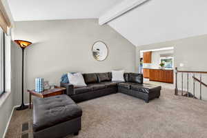 Living room with light carpet, beamed ceiling, and high vaulted ceiling