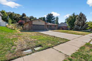 Single story home featuring brick siding, driveway, and an attached garage