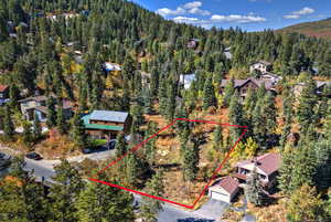 Aerial view of property's location featuring property parcel outlined and a forest