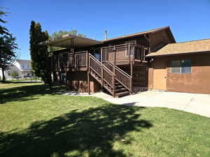 Rear view of house featuring a deck, stairway, and a lawn