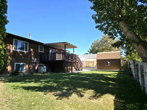 Fenced backyard with stairway, a wooden deck, a storage unit, and a patio area