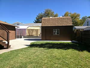 Back of property featuring roof with shingles and a shed