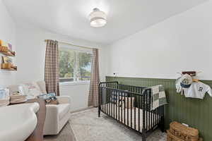 Carpeted bedroom featuring a crib
