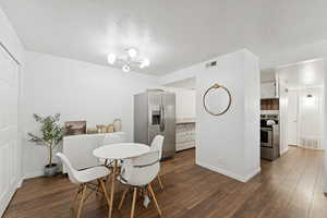 Dining space featuring dark wood-type flooring, a textured ceiling, and a chandelier
