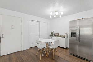 Dining room with dark wood-style floors, a textured ceiling, and a chandelier