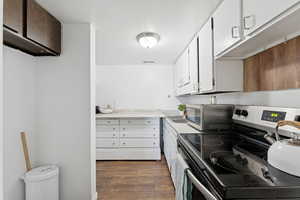 Kitchen with appliances with stainless steel finishes, light countertops, white cabinetry, and dark wood-type flooring