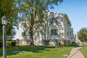 Rear view of property featuring a lawn and brick siding