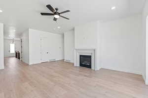 Unfurnished living room with recessed lighting, a glass covered fireplace, light wood-style flooring, and a ceiling fan