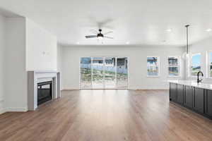 Unfurnished living room featuring light wood-style floors, a fireplace, ceiling fan, a textured ceiling, and recessed lighting