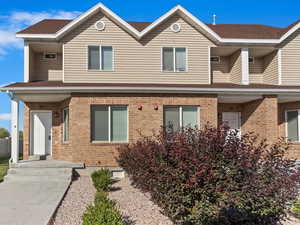 Traditional-style home featuring roof with shingles, brick siding, and covered porch