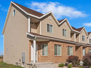 View of front of property featuring a front yard, brick siding, and roof with shingles