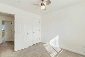 Unfurnished bedroom with carpet, a ceiling fan, and a closet