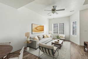 Living room featuring wood finished floors, a ceiling fan, and a textured ceiling. Staged
