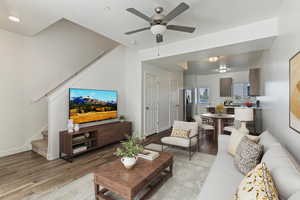 Great room featuring stairway, wood finished floors, and ceiling fan. Staged