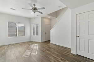 Unfurnished living room and foyer featuring dark wood-style floors, ceiling fan, and a textured ceiling