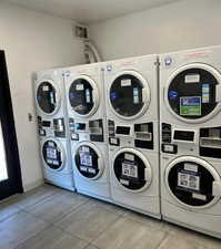Shared laundry room with stacked washer / drying machine and light tile patterned floors