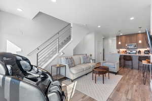 Living room featuring recessed lighting, light wood finished floors, and stairs