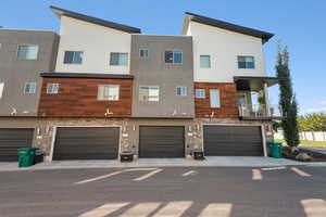 Rear view of property with a balcony, stone siding, and stucco siding