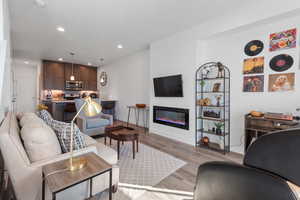 Living area with recessed lighting, light wood finished floors, and a glass covered fireplace