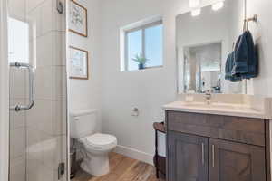 Full bathroom with a stall shower, vanity, and light wood-style floors