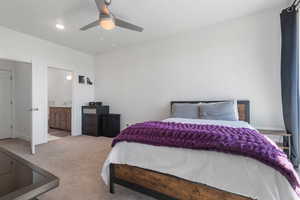 Bedroom featuring carpet floors, ceiling fan, and ensuite bath