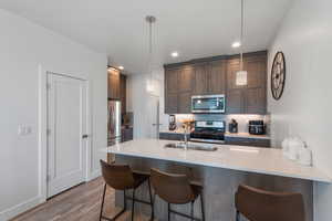 Kitchen with appliances with stainless steel finishes, tasteful backsplash, a kitchen bar, pendant lighting, and recessed lighting