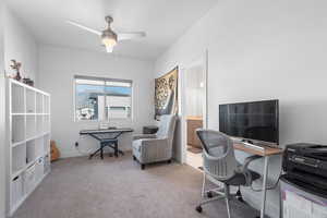 Home office with light carpet and a ceiling fan