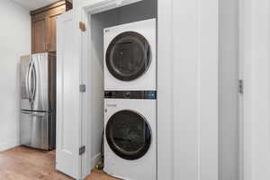 Laundry room with light wood-style flooring and stacked washer / dryer