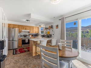 Kitchen with light countertops, appliances with stainless steel finishes, open shelves, backsplash, and a mountain view