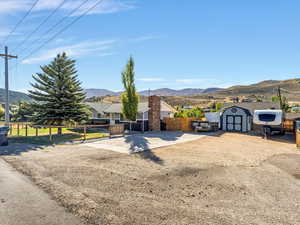 View of front of house featuring a mountain view and a storage shed, RV parking