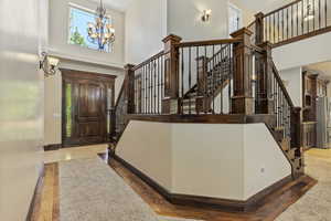 Entryway with a towering ceiling, a chandelier, light wood-style floors, and stairway