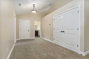 Hall featuring vaulted ceiling and carpet