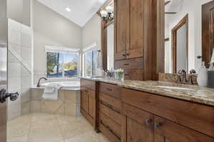 Bathroom featuring double vanity, light tile patterned floors, and a garden tub